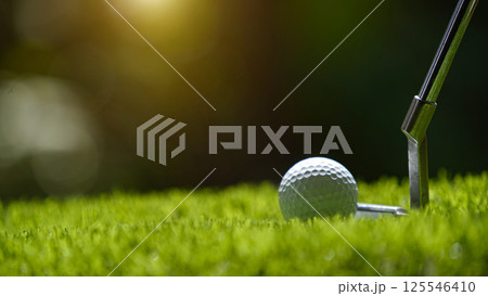 Golf clubs and golf ball on a green lawn in a beautiful golf course with morning sunshine. 125546410