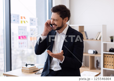 Middle-aged caucasian man in formal suit having phone call in workplace expressing emotions Middle-aged caucasian man in formal suit having phone call in workplace expressing emotions 125546864