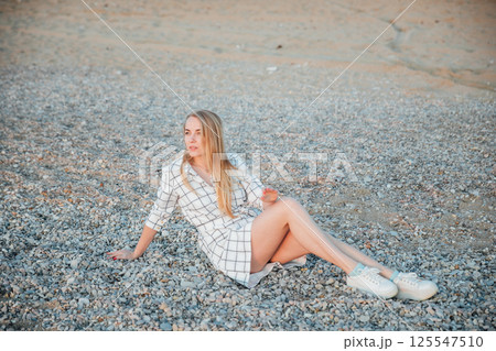 Beautiful blonde woman walking on the beach of the sea Beautiful blonde woman walking on the beach of the sea 125547510