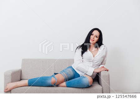 woman relaxing on gray office sofa in white room interior 125547666