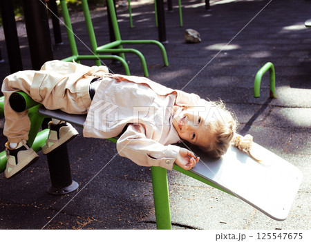 little cute girl with her mother and twin sister having fun on training playground outside little cute girl with her mother and twin sister having fun on training playground outside 125547675