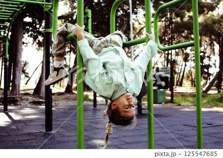 little cute girl with her mother and twin sister having fun on training playground outside 125547685