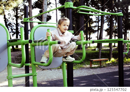 little cute girl with her mother and twin sister having fun on training playground outside little cute girl with her mother and twin sister having fun on training playground outside 125547702