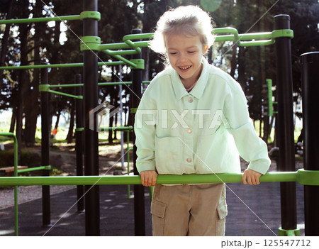 little cute girl with her mother and twin sister having fun on training playground outside 125547712