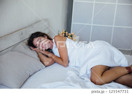 Woman in lingerie sleeping and smiling in a dream in bedroom on bed Woman in lingerie sleeping and smiling in a dream in bedroom on bed 125547731