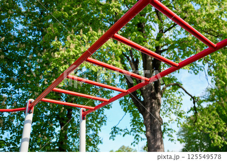 Red outdoor monkey bars in park with green trees Red outdoor monkey bars in park with green trees 125549578