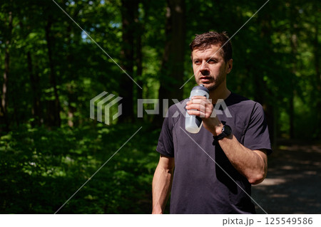Man drinking water after outdoor run in forest 125549586