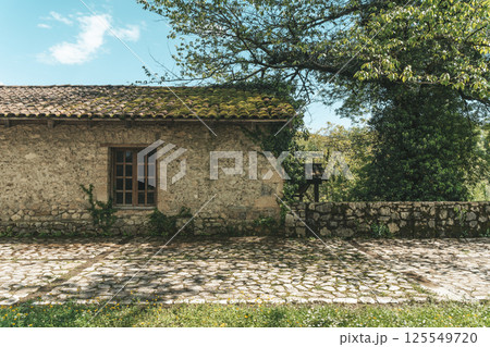 Old European village stone house with windows and tiled roof 125549720