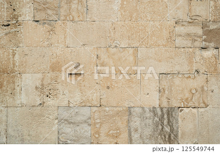 Antique ancient stone wall masonry texture background. Old wall made of beige stone blocks Antique ancient stone wall masonry texture background. Old wall made of beige stone blocks 125549744