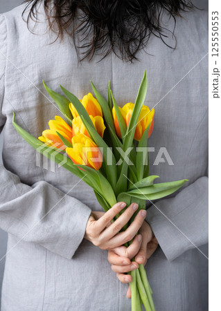 woman holds bouquet of yellow-red tulips in hands. birthday or mother's day gift. view from back. 125550553