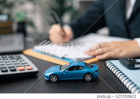 Dealership offered various finance options, including an auto loan or lease, making it easier to buy or rent a car from the company. Agent reviewed contract, finalizing insurance agreement. 125550621