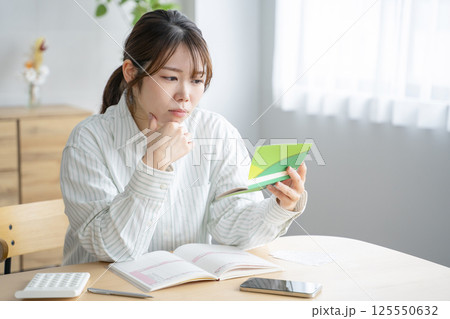 通帳を眺める女性 125550632