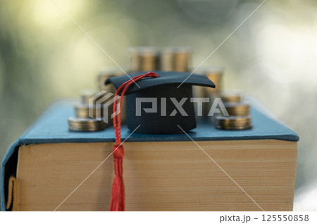 Graduation from college with university degree in finance marked successful culmination of education, envisioning value of each coin invested. coin, college, education, graduation, hat, school. Graduation from college with university degree in finance marked successful culmination of education, envisioning value of each coin invested. coin, college, education, graduation, hat, school. 125550858