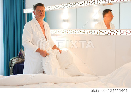 Morning chores, man in robe making bed after sleep, daily household duties 125551401