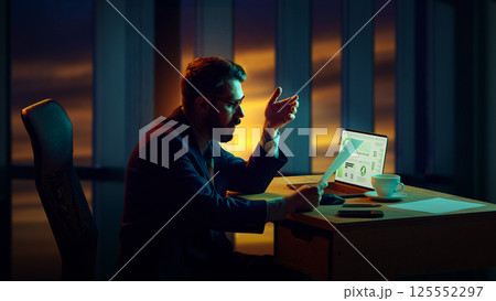 Businessman sitting in his office late, reviewing financial reports during business crisis, working on strategies. Laptop with analytics. 125552297