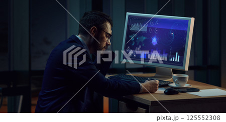 Sad and tired businessman sitting at desk with computer monitor showing analytics, working late night, analyzing data charts on screen. Sad and tired businessman sitting at desk with computer monitor showing analytics, working late night, analyzing data charts on screen. 125552308