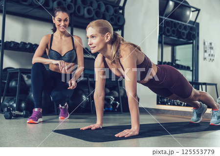 Coach in the gym working with a customer and both looking involved 125553779