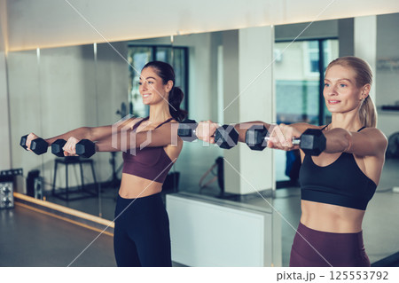 Two young caucasian women exercising with dumbbells and looking focused 125553792