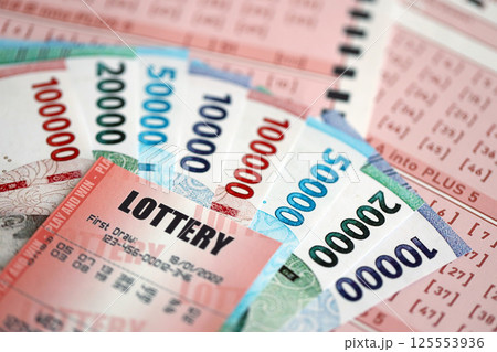 Red lottery ticket lies on pink gambling sheets with indonesian rupiah money bills. Lottery playing concept or gambling addiction in indonesia 125553936