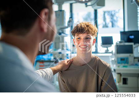 Teenage boy smiling during medical consultation after receiving positive health news. 125554033
