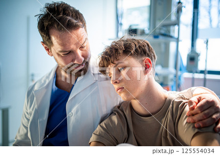 Compassionate doctor supporting anxious teenage patient before surgery. 125554034