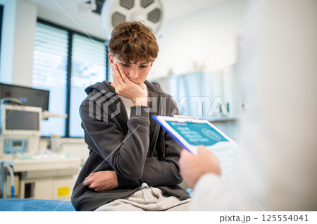 Doctor and teenage patient filling out mental health evaluation form. 125554041