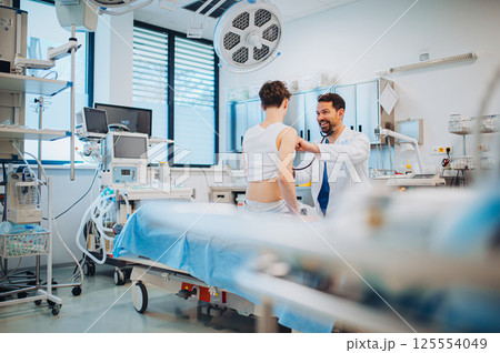 Teen boy undergoing medical checkup with doctor in hospital room. 125554049