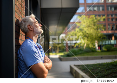 Frustrated and burnt-out doctor sitting outside the hospital, feeling down. Frustrated and burnt-out doctor sitting outside the hospital, feeling down. 125554092