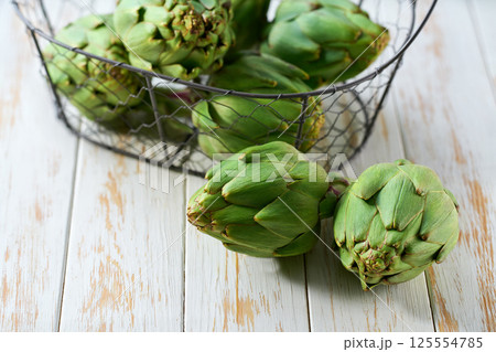 Fresh green artichoke in a metall basket on a wooden table selective focus. 125554785