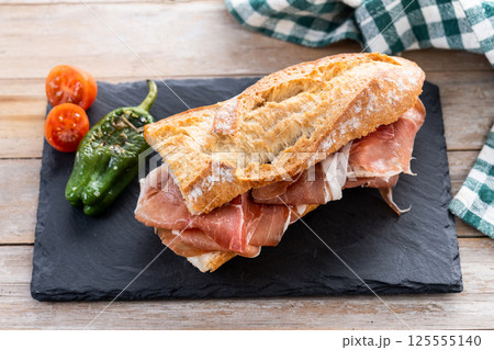 Spanish serrano ham sandwich on wooden table. Spanish bocadillo de jamon serrano 125555140