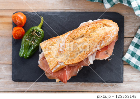 Spanish serrano ham sandwich on wooden table. Spanish bocadillo de jamon serrano 125555148