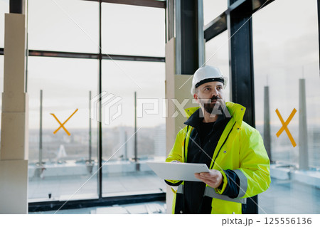Construction site manager using digital tablet to inspect building progress. Construction site manager using digital tablet to inspect building progress. 125556136