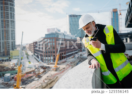 Site manager giving instructions over radio during building inspection. 125556145