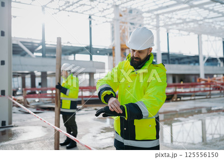 Construction workers at work on modern building site. 125556150