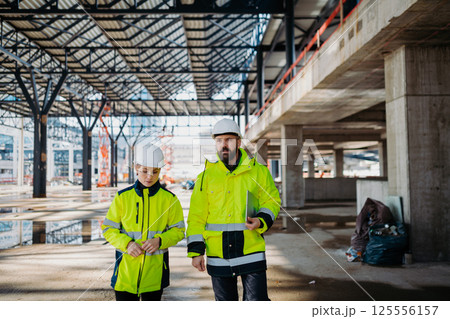 Engineers discussing construction plans using a tablet on site. Engineers discussing construction plans using a tablet on site. 125556157