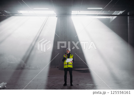 Construction foreman giving instructions over radio during building inspection. 125556161