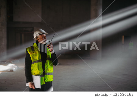 Construction foreman giving instructions over radio during building inspection. Construction foreman giving instructions over radio during building inspection. 125556165