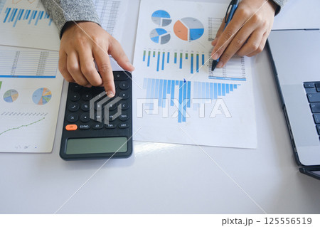 Close up accountant banker or bookkeeper making calculations with calculator. 125556519