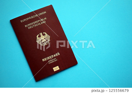 Red German passport of European Union on blue background close up Red German passport of European Union on blue background close up 125556679