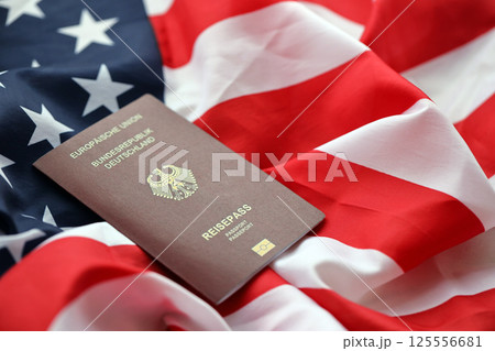 Red German passport of European Union on United States national flag background close up Red German passport of European Union on United States national flag background close up 125556681