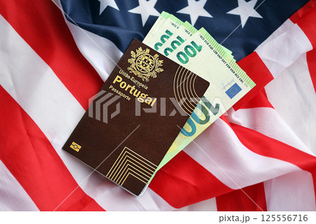 Red Portugal passport of European Union and money on United States national flag background Red Portugal passport of European Union and money on United States national flag background 125556716