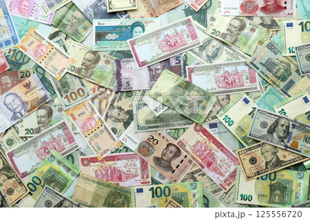 Many banknotes of different currency. Background of big amount of random money bills Many banknotes of different currency. Background of big amount of random money bills 125556720