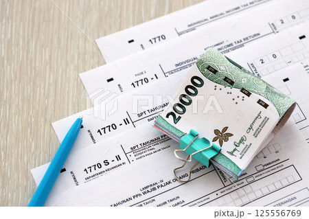 Annual Individual Income Tax Return forms with pen and indonesian rupiah bills Annual Individual Income Tax Return forms with pen and indonesian rupiah bills 125556769
