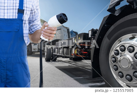 Hand with charging plug on a background of electric truck 125557005
