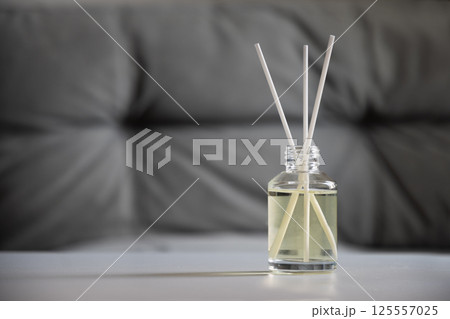 Aromatherapy reed diffuser bottle with fragrance oil and sticks on a gray blurred background. Home interior. Wellness and relaxation Aromatherapy reed diffuser bottle with fragrance oil and sticks on a gray blurred background. Home interior. Wellness and relaxation 125557025