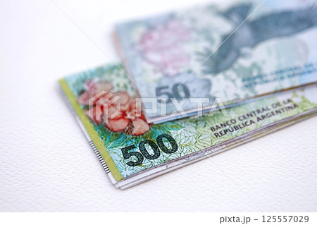 Argentine pesos money bills in big amount lies on white table close up Argentine pesos money bills in big amount lies on white table close up 125557029