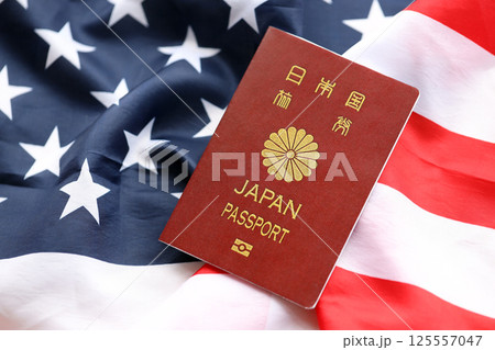 Japan passport on United States national flag background close up. Tourism and diplomacy 125557047