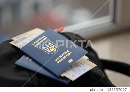 Two ukrainian biometrical passports with air flight tickets on black touristic backpack 125557097