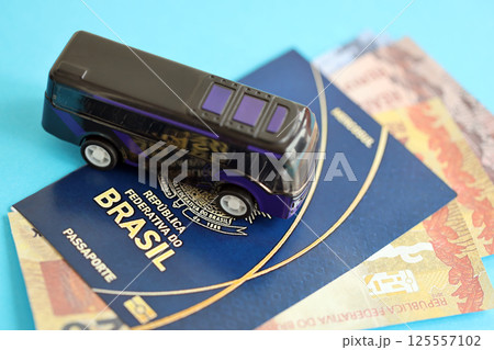 Blue Brazilian passport with money and small bus on blue background close up Blue Brazilian passport with money and small bus on blue background close up 125557102