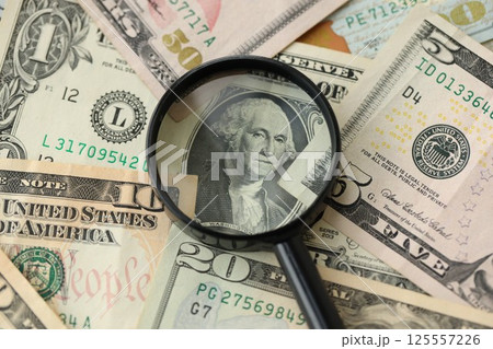 Big amount of United States USD dollar bills and magnifying glass Big amount of United States USD dollar bills and magnifying glass 125557226